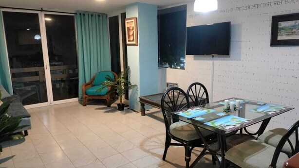 Un coin repas avec une table en verre, des chaises et une plante en pot.