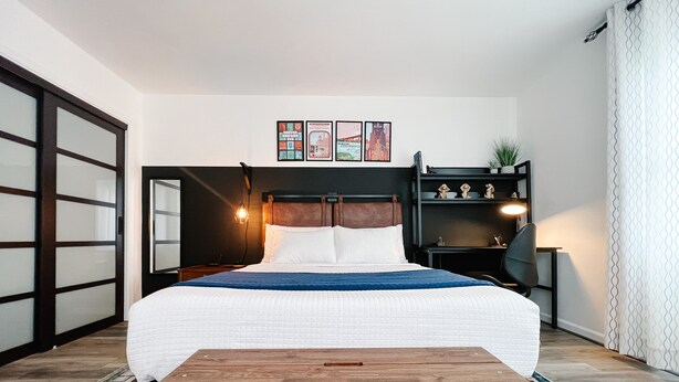 Une chambre à coucher comprenant un lit, une table de chevet en bois, un bureau et une étagère.