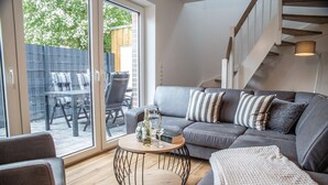 A modern living room with a grey sofa, striped pillows, a round coffee table, and a staircase.