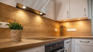 A modern kitchen with wooden countertops, a built-in oven, and a potted plant.