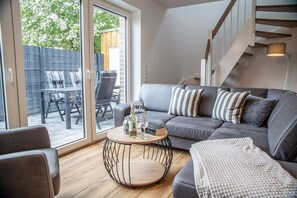 En moderne stue med en grå sofa, stribede puder, et rundt sofabord og en trappe.