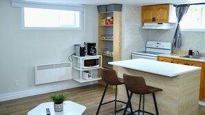 Una cocina compacta con una isla central, armarios de madera y un microondas integrado.