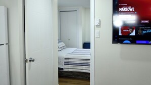 Una habitación de hotel con una cama, un televisor mostrando una película y una puerta que da a otra habitación.
