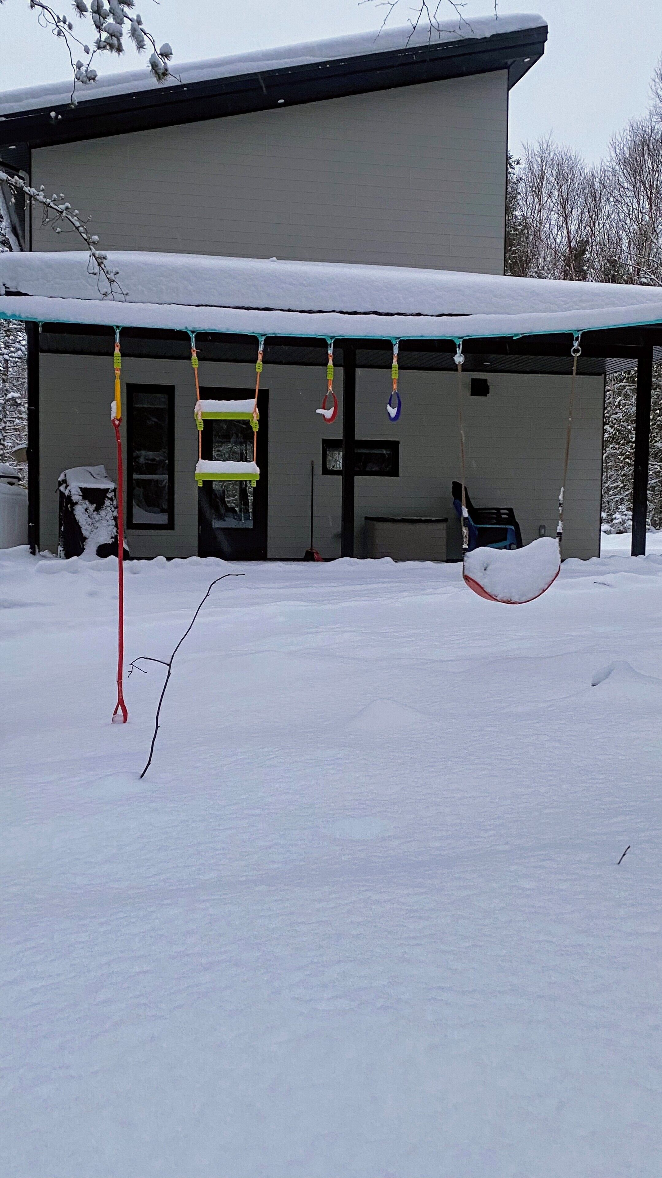 Un edificio con un portico coperto e un'altalena, immerso nella neve.