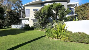 A modern two-story house with a well-maintained lawn and a variety of plants. - 2 The Pier - Elegance by the Water (Tea Gardens)
