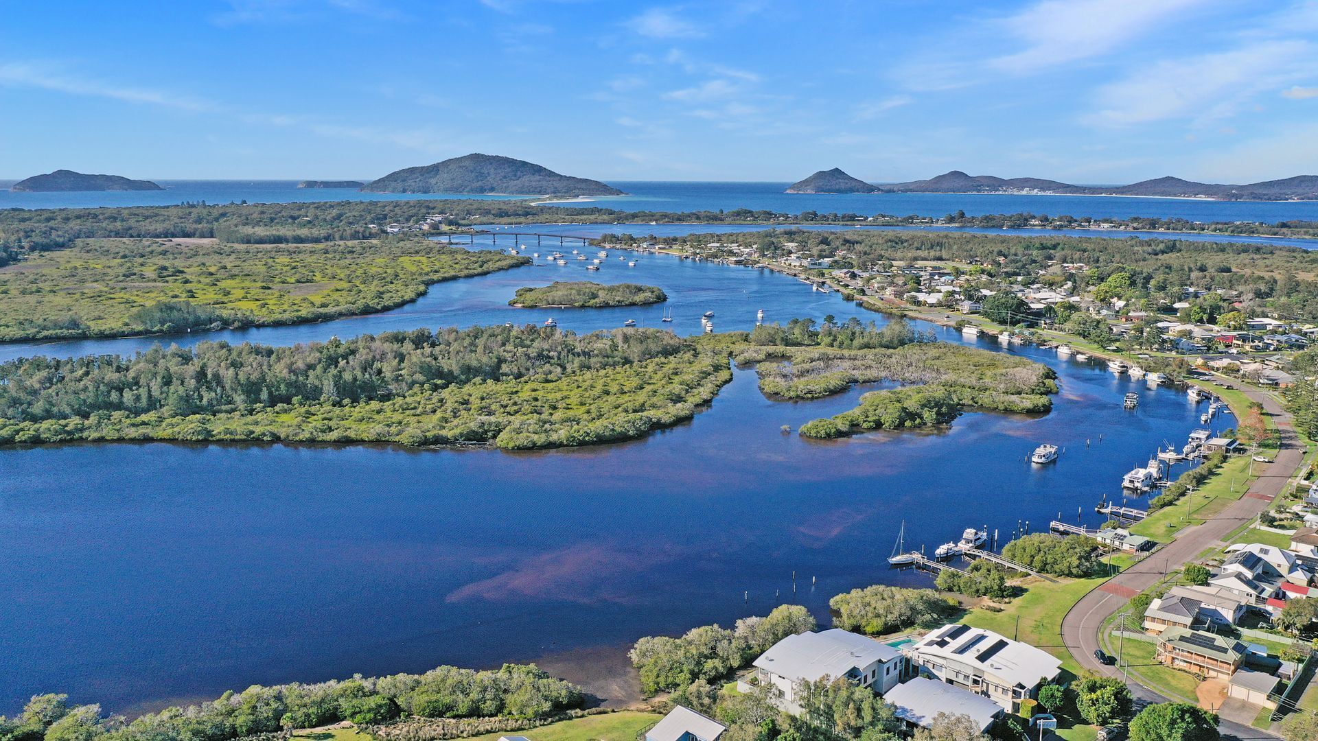 Vista aèria d'una zona costanera amb un port esportiu, edificis residencials i paisatges naturals.