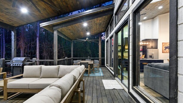 Une terrasse en bois avec un canapé, une table et des chaises, ainsi qu’un ventilateur de plafond.