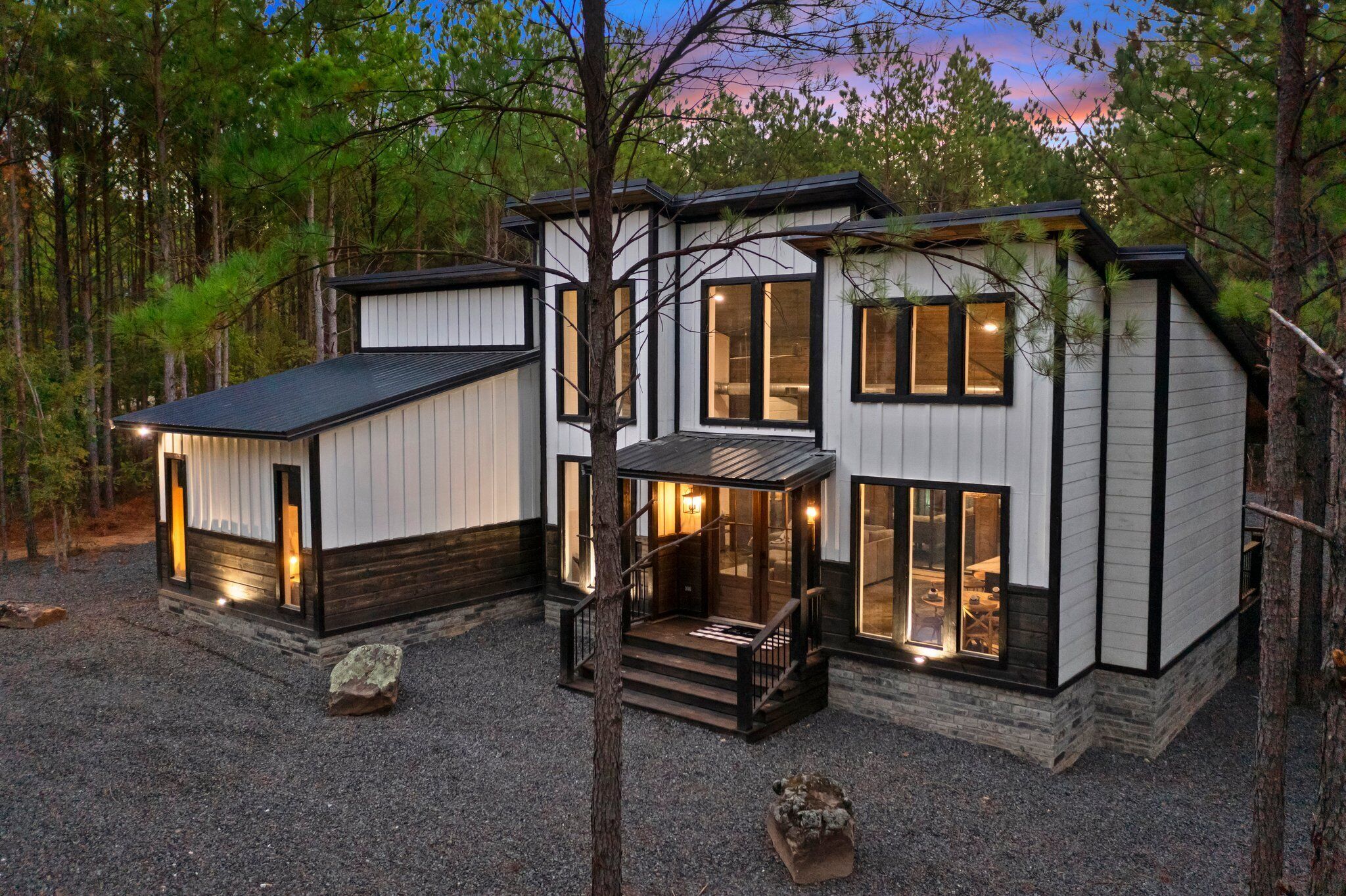 Een modern huis met een ruime veranda, meerdere ramen en een stenen fundering.