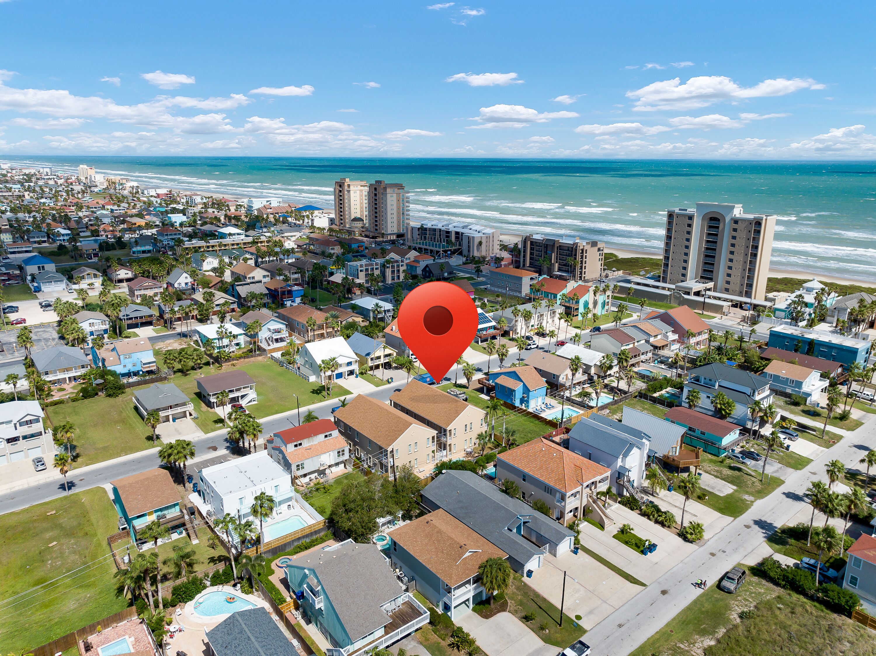 An aerial view of a coastal residential area with a red location marker. - Cozy Coastal Escape w/ Pool - 1/2 Block to Beach! (South Padre Island)