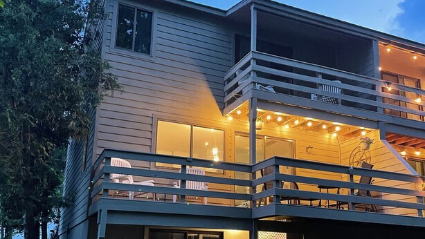 A two-story house with a balcony and string lights.