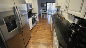 A kitchen with white cabinets, stainless steel appliances, and a 'Live. Love. Eat.' sign.