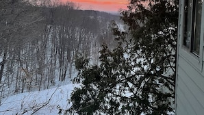 A snowy landscape with a sunset view, trees, and a building.