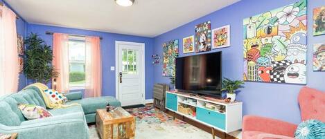 A living room with a sofa, a coffee table, a TV, and artwork on the walls.