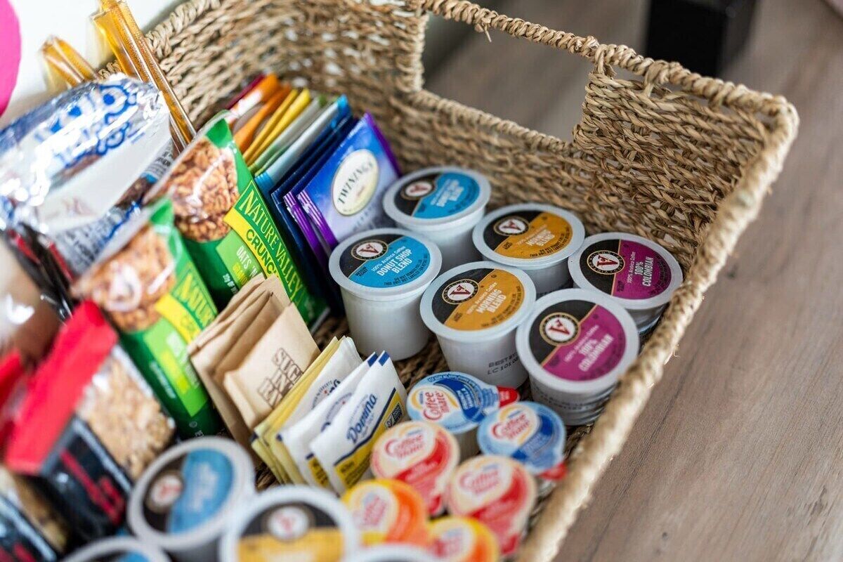 Ein Korankorb gefüllt mit verschiedenen verpackten Lebensmitteln, darunter Snacks und Kaffee.