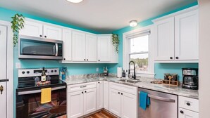 A modern kitchen with white cabinets, a stainless steel oven, a microwave, and a dishwasher.