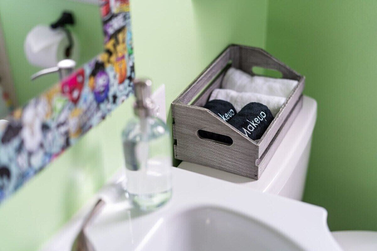 A bathroom with a wooden box containing black items labeled 'makeup' on a white sink.
