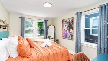 A bedroom with a bed, a chair, a window, and a painting.