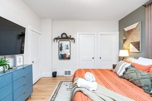 Ein Schlafzimmer mit Bett, Kommode, Fernseher und Spiegel.