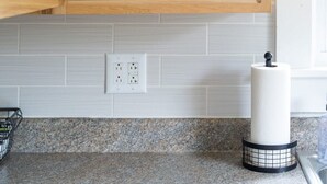 Um armário de cozinha com prateleiras contendo canecas de cerâmica branca e potes de vidro.