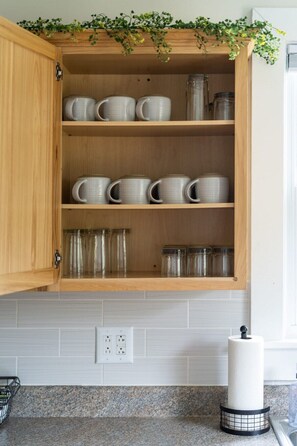 A kitchen cabinet with shelves holding white ceramic mugs and glass jars. - Gypsy Haven: Walk Downtown + Sunroom (Staunton)