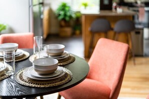 A dining table set with plates, bowls, and glasses, accompanied by woven placemats. - Gypsy Haven: Walk Downtown + Sunroom (Staunton)