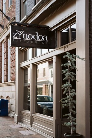 Fachada com uma placa indicando 'Zynodoa Restaurant' e o número '115' acima da entrada.