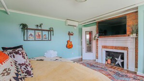 Een kamer met een bed, een open haard, een gitaar aan de muur en een televisie.