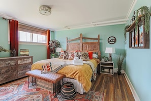 Een gezellige slaapkamer met een houten bed, een bankje, een kaptafel en een raam met gordijnen.