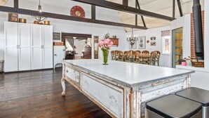 Une cuisine spacieuse dotée d’un grand îlot central, de poutres en bois et d’une esthétique rustique.