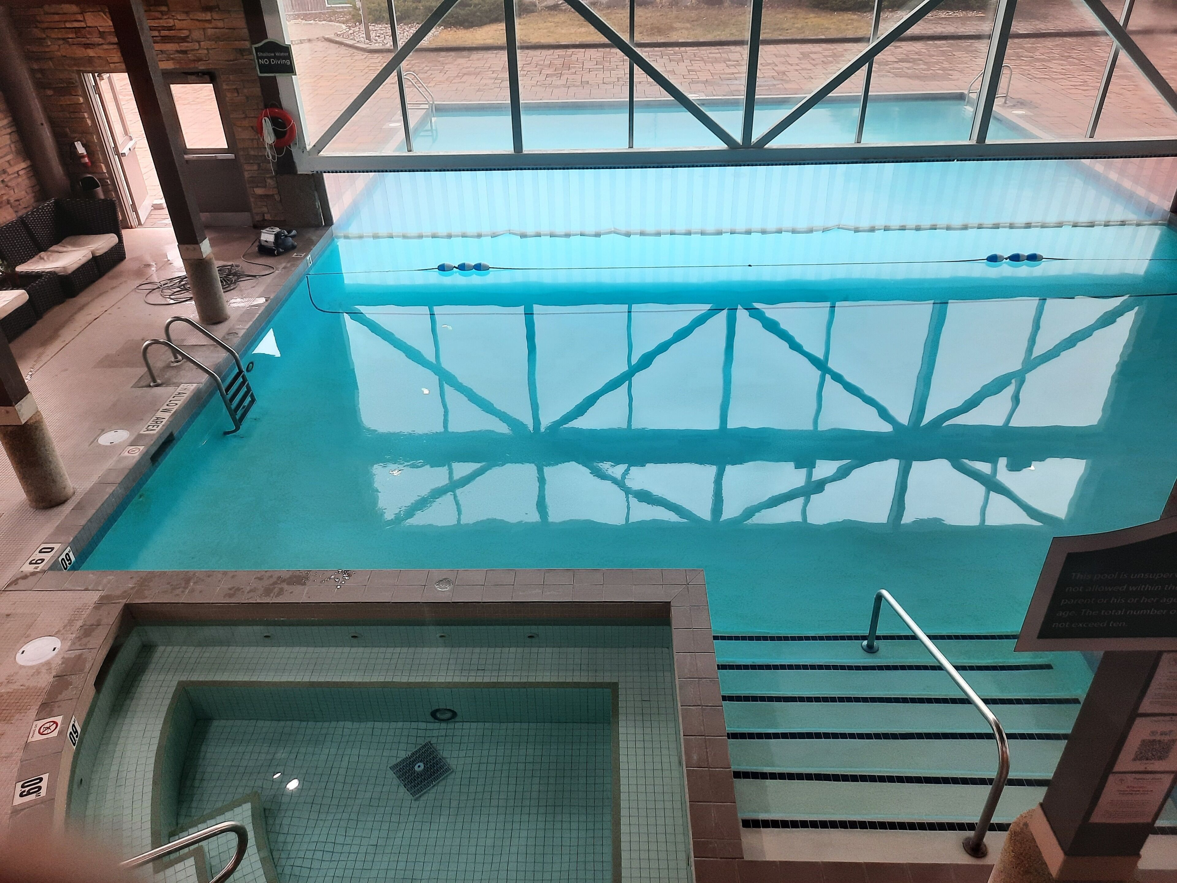 Une piscine intérieure à l’eau claire, dotée d’un plongeoir et d’un espace séparé avec un bain à remous.