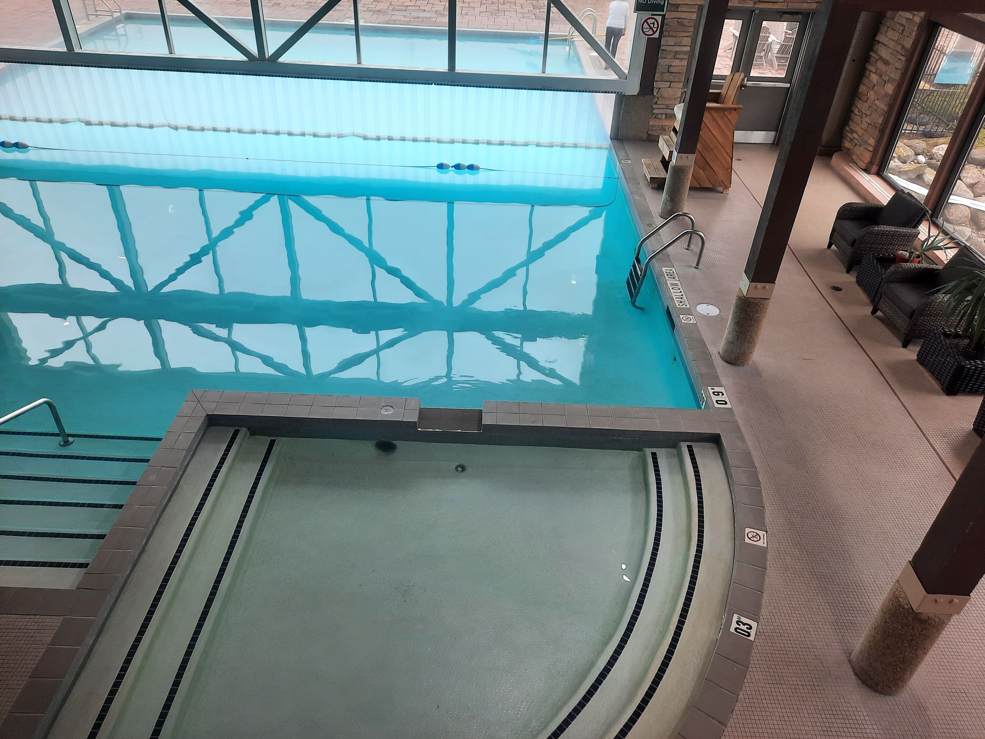 Ein Poolbereich mit Sprungbrett, Liegestühlen und Whirlpool.
