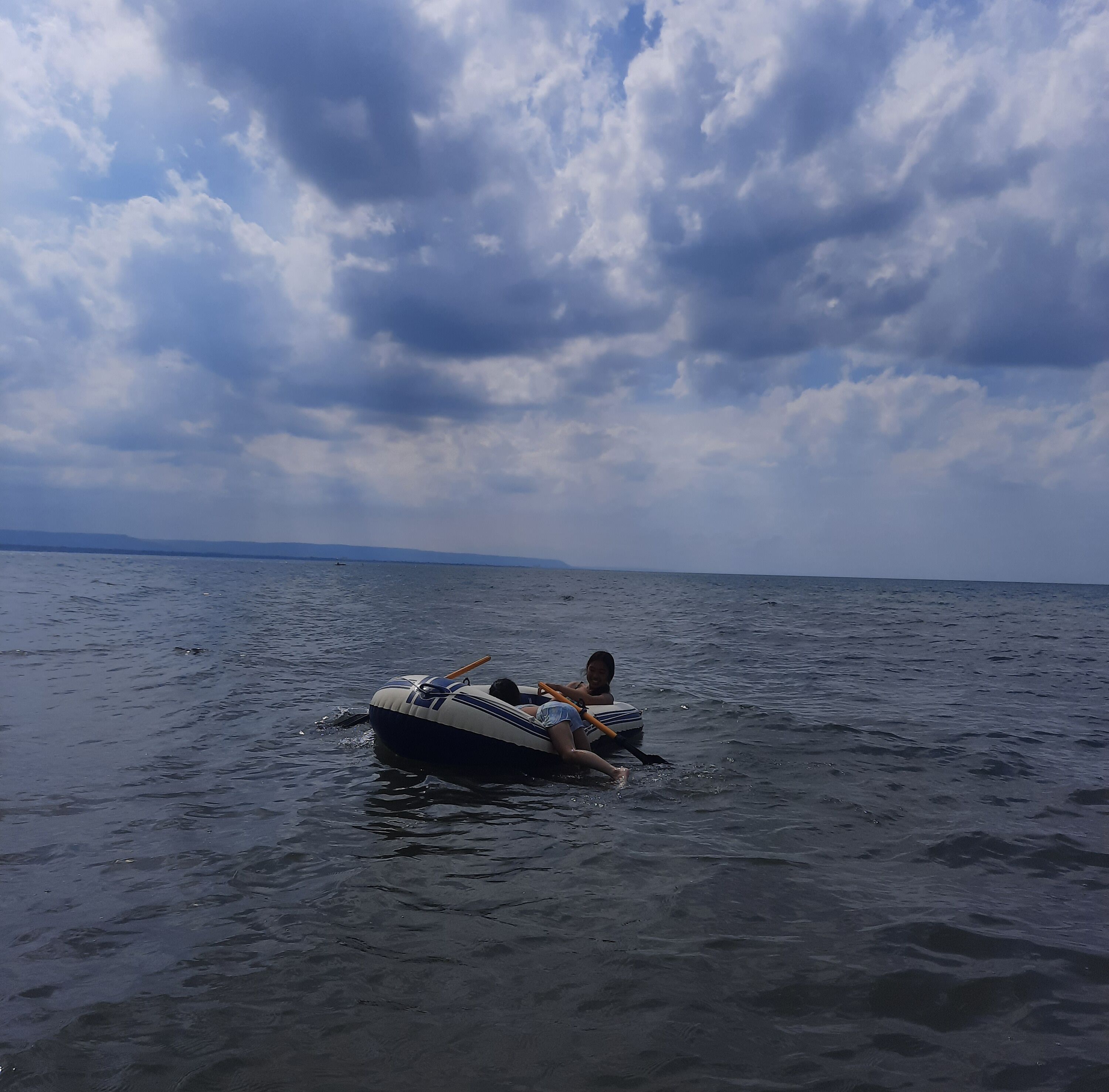 A boat on calm water with a cloudy sky above.