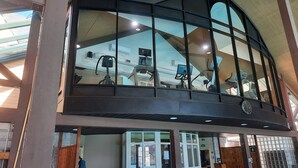 A modern building with a large glass enclosure, a staircase, and a view of exercise equipment.