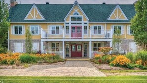 A two-story house with a front porch, a red door, and a balcony.