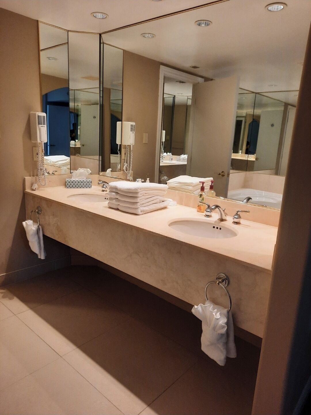 Un baño moderno con un espejo grande, dos lavamanos y un perchero para toallas.