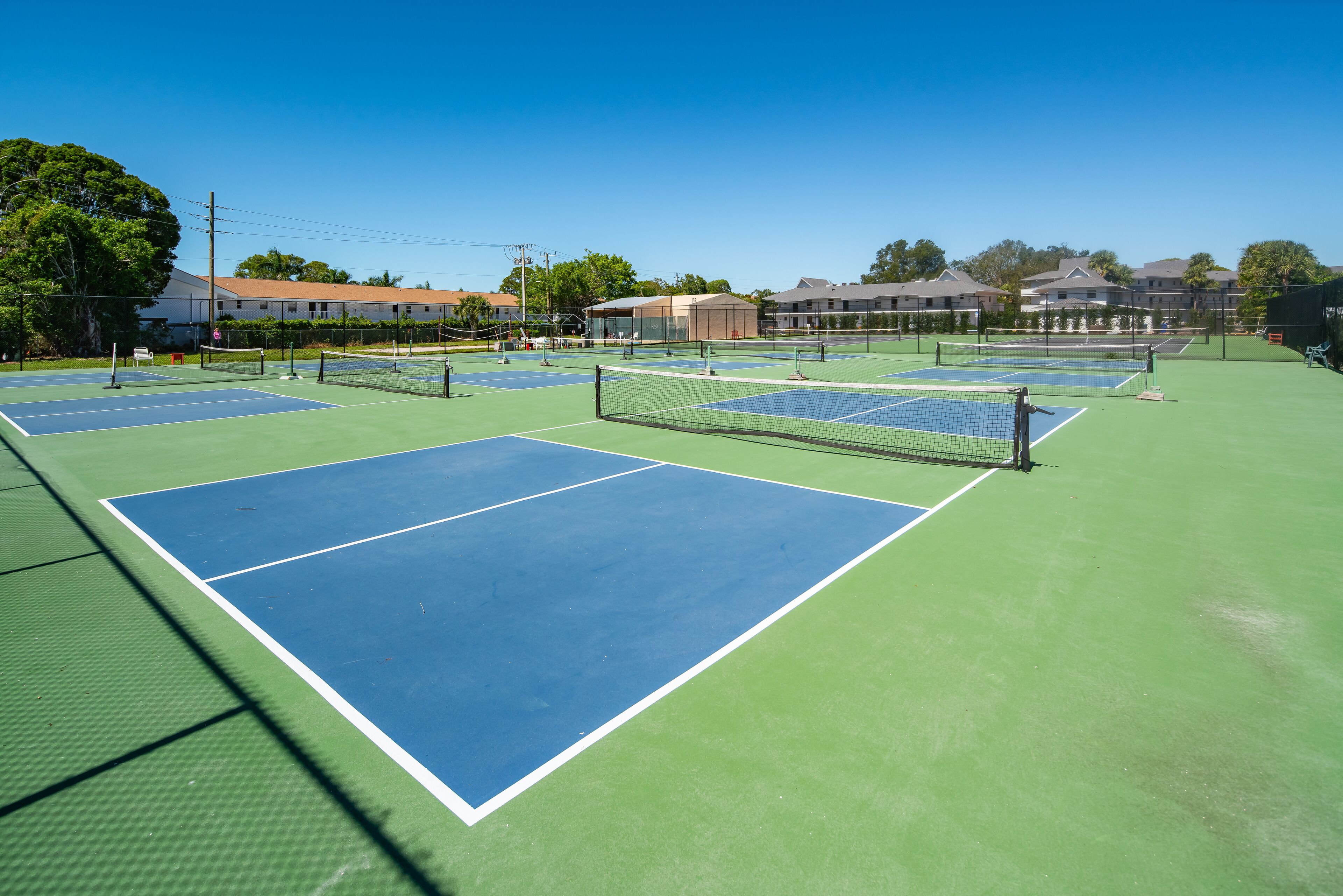 A tennis court with multiple courts, surrounded by buildings and trees.