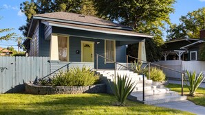 A two-story house with a front porch, a stone planter, and a small garden. - Welcome to Casa Azul 1932 Eclectic Boho Sanctuary  in Downtown Riverside! (Riverside)