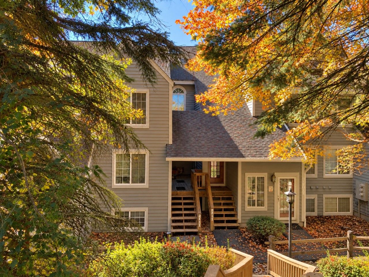 A two-story house with a front porch, a staircase leading to the entrance, and a small garden area.