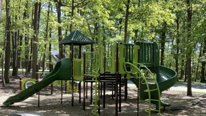 A playground with a slide, climbing structures, and a small shelter.