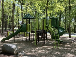 Un parque infantil con tobogán, estructuras para escalar y un pequeño refugio.