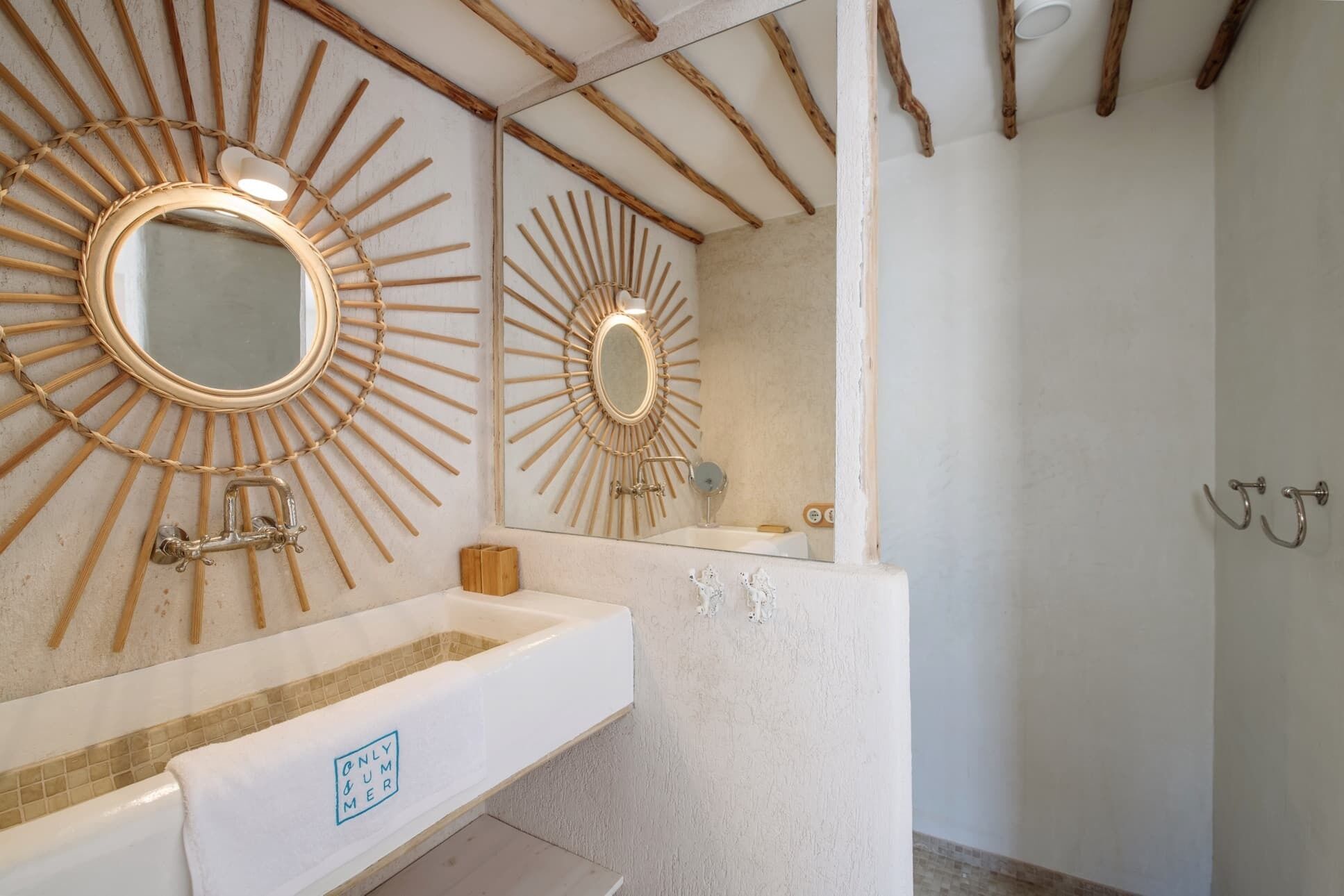Un baño con un espejo diseño sol, un lavabo blanco y una zona de ducha.