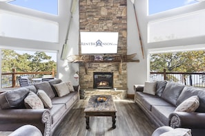 A cozy living room with a stone fireplace, leather sofas, and a wooden coffee table.