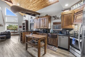 Una cocina amplia con armarios de madera, un refrigerador de acero inoxidable y un comedor con mesa de madera.
