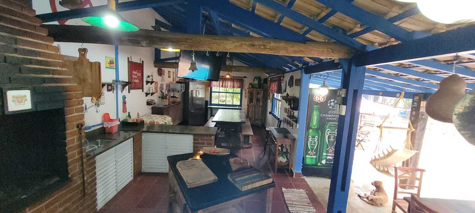 Et hyggeligt køkken med murstensvæg, træloft og en hængende lampe. Der er et bord med et lys og en stol.