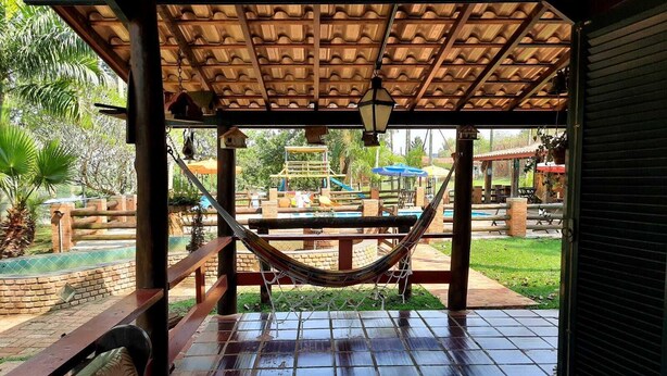 A covered patio with a hammock, a pool, and outdoor seating.