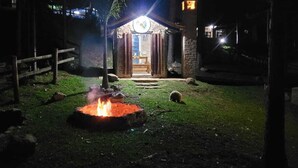 A rustic outdoor area with a fire pit, a wooden fence, and a stone building entrance.