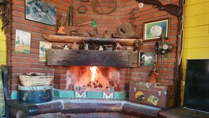 A cozy room with a brick fireplace, surrounded by various decorative items and a television on a wooden stand.