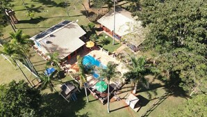 An aerial view of a property with a swimming pool, outdoor seating, and a covered patio area.