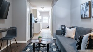Una sala de estar moderna con un sofá gris, una mesa de centro y un televisor montado en la pared.