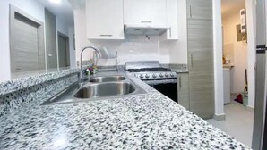 Een moderne keuken met granieten aanrecht, roestvrijstalen apparatuur en witte keukenkastjes.
